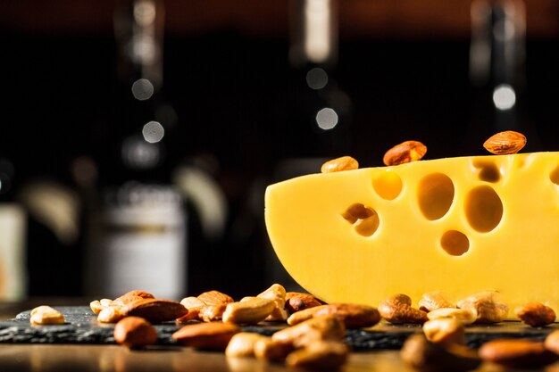 Almonds and peanuts lie on piece of Swiss cheese