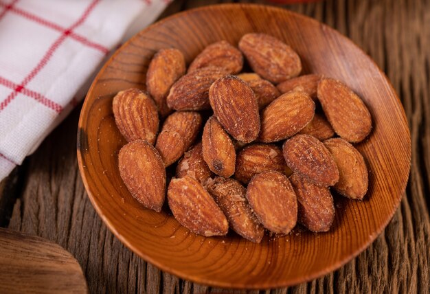 Almonds sprinkled with salt in a plate on a wooden table