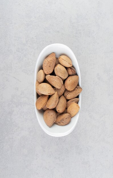 Almonds in the white bowl, on the marble surface