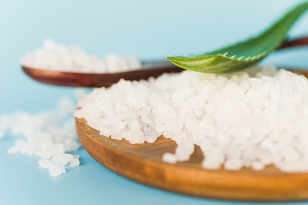 Free photo aloe vera leaf on rock salt over the wooden tray on blue background