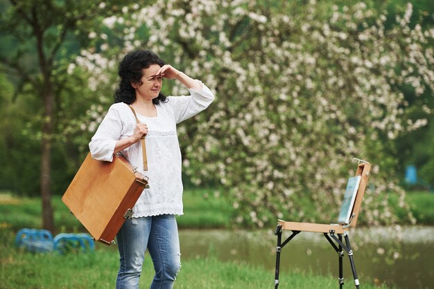 Alone in the park. Mature painter with case of instruments have a walk