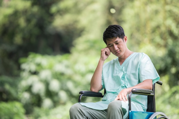 Alone young disabled man in wheelchair at the garden