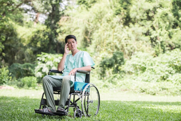 Один молодой инвалид в инвалидной коляске в саду