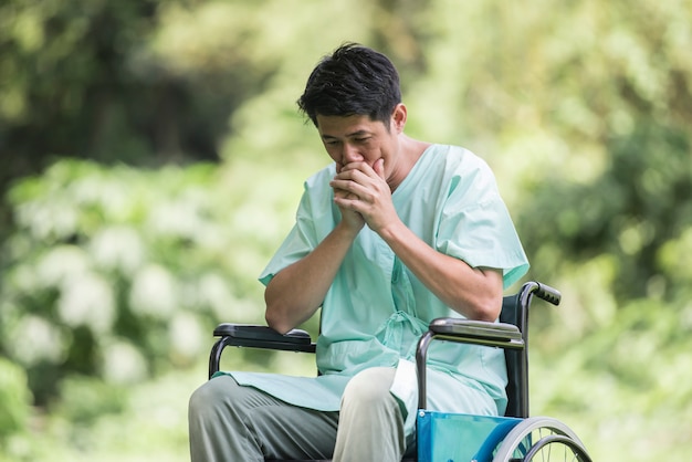 Free photo alone young disabled man in wheelchair at the garden