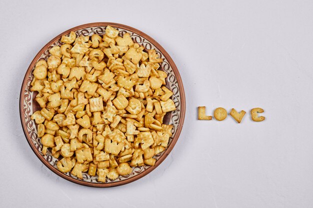 Alphabet crackers on a ceramic plate and word love spelled with crackers.