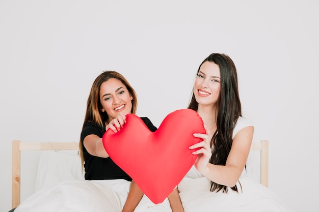 Alternative female couple with heart on bed