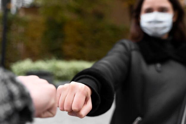 Alternative greetings almost touching fist bumps blurred woman