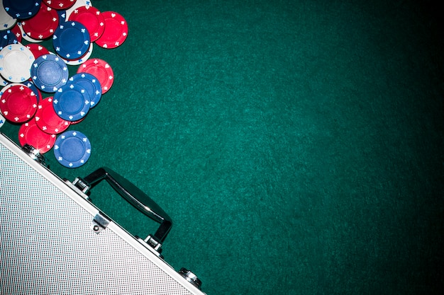 Aluminium suitcase with casino chips on green background