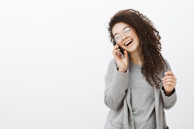 Always fun talking to you. Positive happy young european female photographer in stylish coat and glasses, laughing out loud