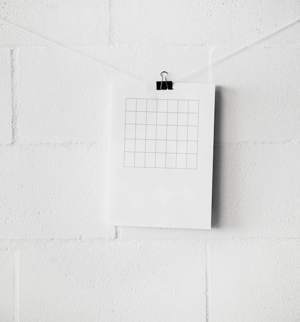 Am empty table over paper attach on string with paperclip against white wall