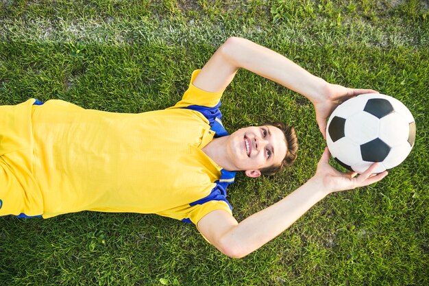 ボールを投げる横たわった男とアマチュアフットボールのコンセプト