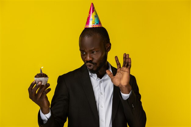 Amazed beautiful African man makes a wry face while holding a cake