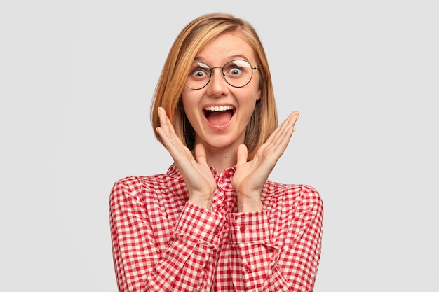 Free photo amazed beautiful young european woman has joyful expression notices desirable thing in shop