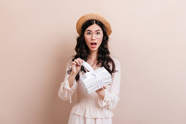 Amazed chinese woman opening gift. Studio shot of surprised asian woman with birthday present.