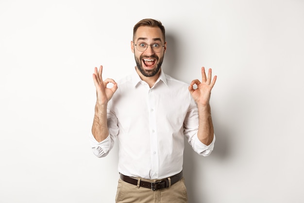 Amazed entrepreneur showing okay sign and looking happy, satisfied with product, standing  white