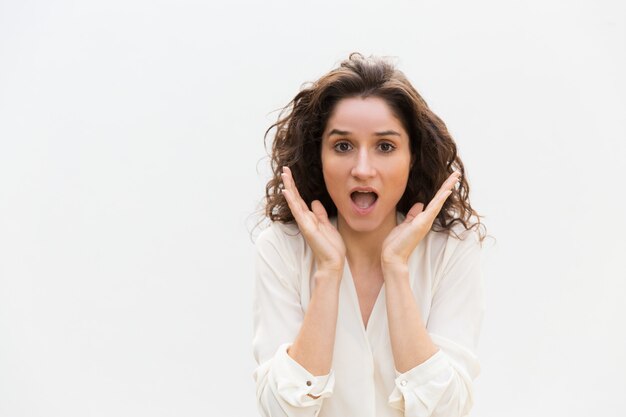 Amazed excited woman gasping, keeping hands at open mouth