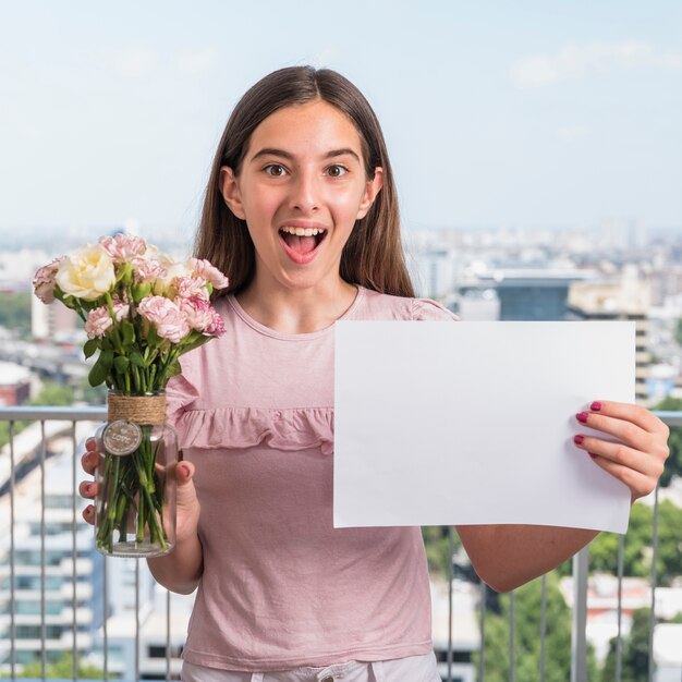 Amazed girl standing with flowers and paper 