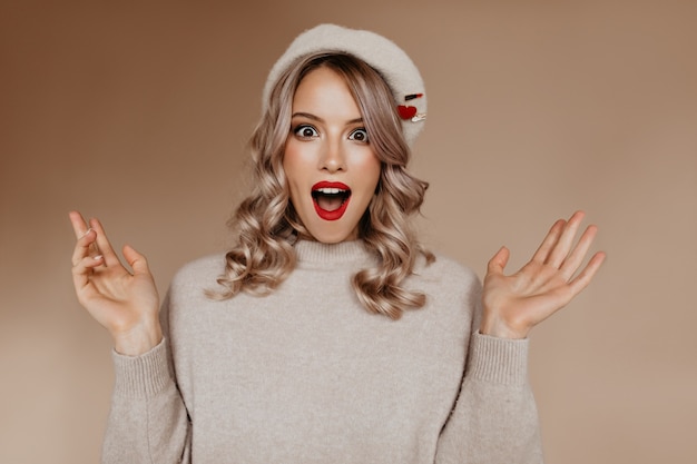 Amazed good-looking french woman in brown beret standing in studio