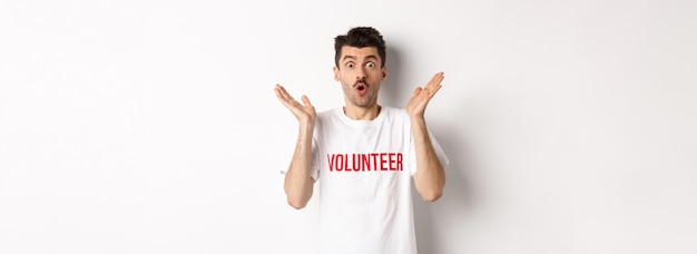 Free photo amazed male volunteer in white tshirt hear great news clap hands and staring at camera surprised pos