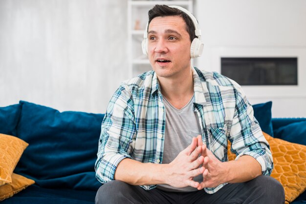 Amazed man listening music in headphones on sofa