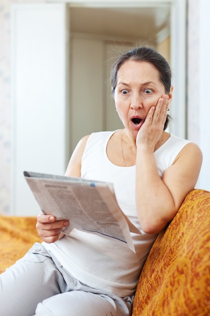 amazed mature woman looks newspaper