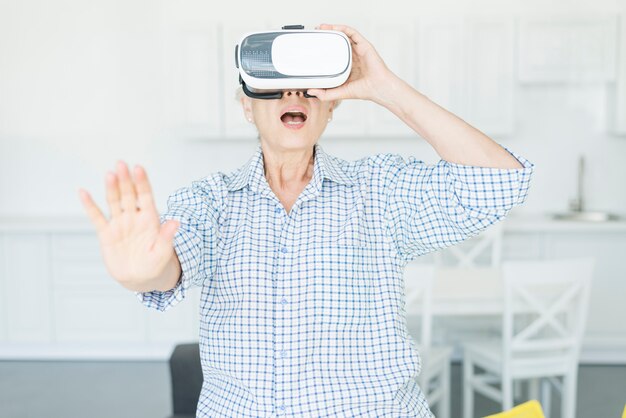 Amazed senior woman touching the air during the VR experience