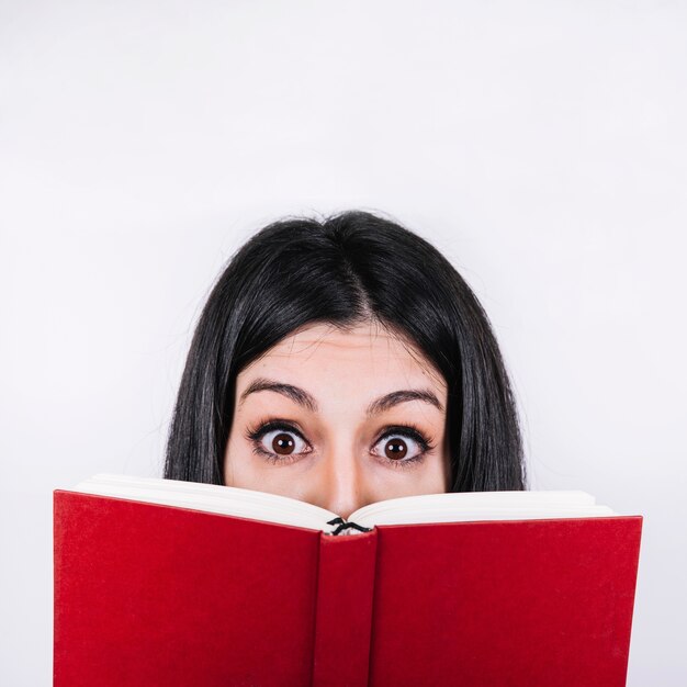 Amazed woman behind book