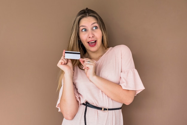 Amazed woman in dress standing with credit card