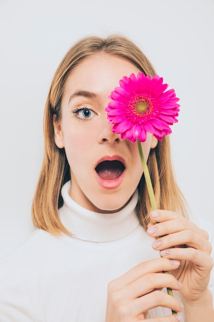 Free photo amazed woman holding gerbera flower at face