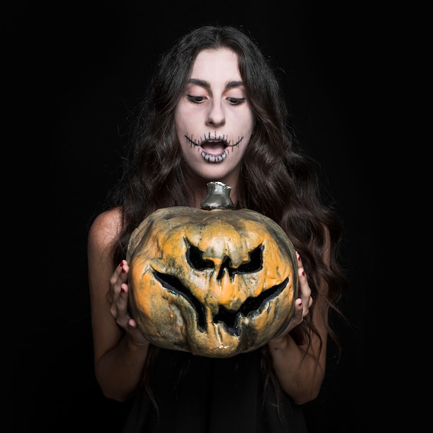 Free photo amazed woman holding halloween pumpkin