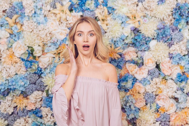 Amazed woman standing on flowers background 