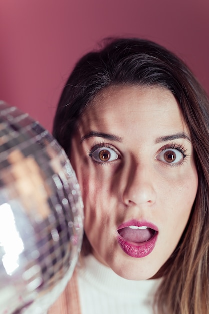 Free photo amazed woman standing with disco ball