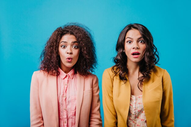 amazed women standing on bright blue wall