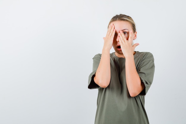 Amazed young girl covering her face with hands on white background