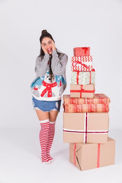 Amazed young woman near heap of presents 