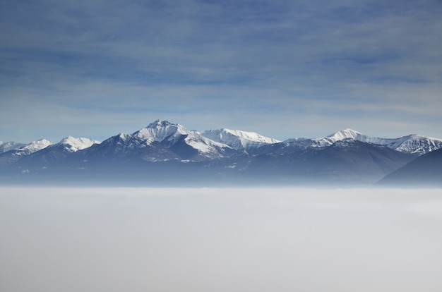 Amazing aerial view of mountains partially covered with snow and positioned higher than clouds