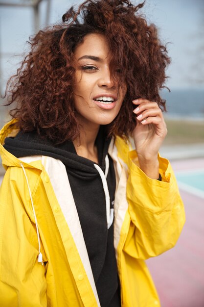 Amazing african curly young woman wearing yellow coat