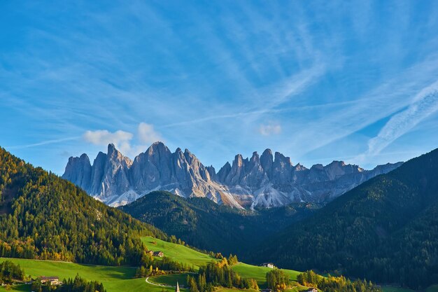 Amazing autumn scenery in Santa Maddalena village with church colorful trees and meadows under rising sun rays Dolomite Alps Italy