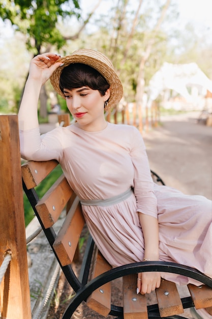 Free photo amazing brunette girl comfortably settled on a wooden bench and thinking about something