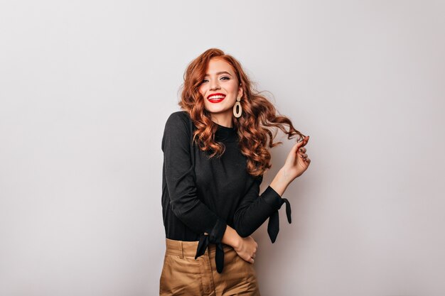 Amazing caucasian girl with long ginger hair posing with smile.  carefree graceful woman in black blouse.