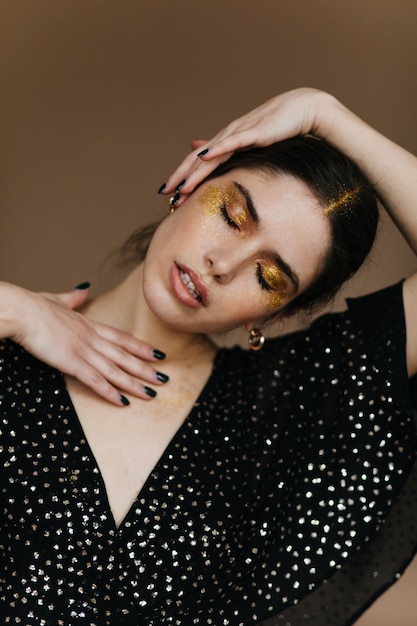 Amazing caucasian lady with bright makeup posing with eyes closed.  relaxed model in black blouse.