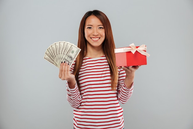 Free photo amazing emotional young asian lady holding gift and money.