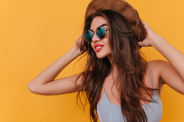 Amazing female model with romantic hairstyle touching her hat and looking away with pensive face expression