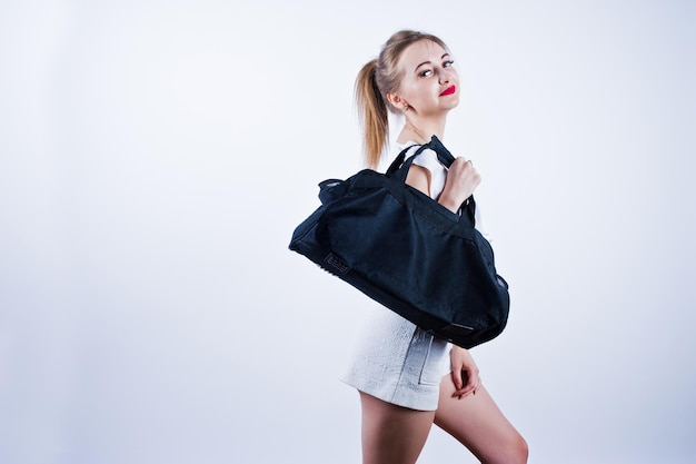 Free photo amazing fit sexy body brunette caucasian girl posing at studio against white background on shorts and top with black sport bag