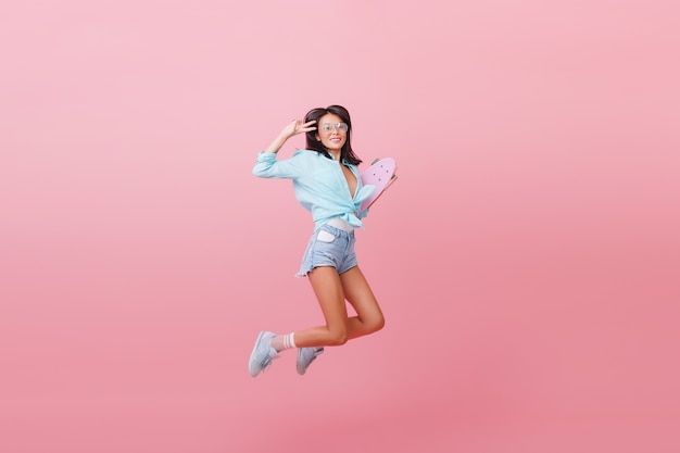 스케이트 보드와 함께 점프 거리 복장에 놀라운 라틴 유행 소녀. 청바지 반바지와 줄무늬 양말 재미 유행 여자
