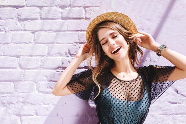 Amazing long-haired girl in stylish clothes enjoying good day outside standing with eyes closed under sun