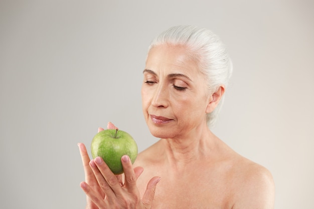 Amazing naked elderly woman holding apple.