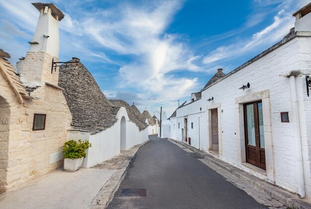 녹색 식물과 꽃 사이에 Trulli 주택이 있는 놀라운 Alberobello 마을, 주요 관광 지구, 남부 이탈리아 Apulia 지역. 마른 돌담과 원추형 지붕으로 지어진 전형적인 건물.