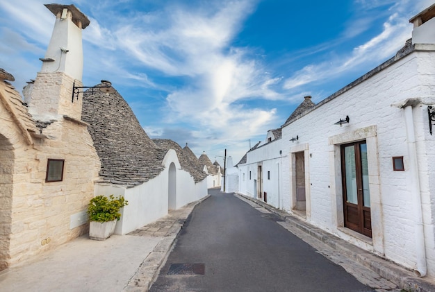 녹색 식물과 꽃 사이에 Trulli 주택이 있는 놀라운 Alberobello 마을, 주요 관광 지구, 남부 이탈리아 Apulia 지역. 마른 돌담과 원추형 지붕으로 지어진 전형적인 건물.