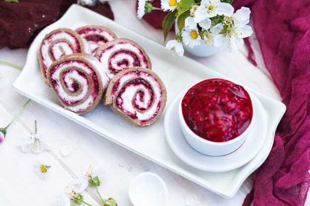 Amazing view of tasty looking raspberry rolls and raspberry jam put on a white plate